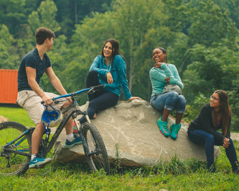 4 teens around a large rock